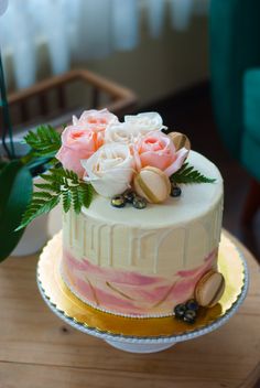 a white and pink cake sitting on top of a wooden table