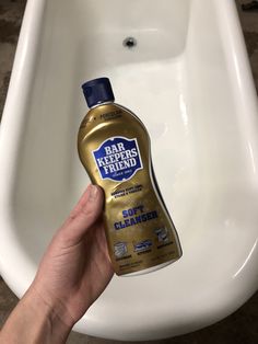 a hand is holding a bottle of soap in front of a urinal that has been cleaned