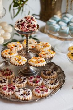 desserts and pastries are displayed on a silver platter at a wedding reception