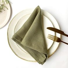 a white plate topped with a green napkin next to a fork and knife on top of it