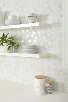 two white shelves with plates and cups on them, one has a potted plant