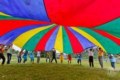 people holding up large colorful kites in a field