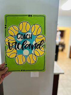 a hand holding up a sticker that says coach bicolore in front of a refrigerator