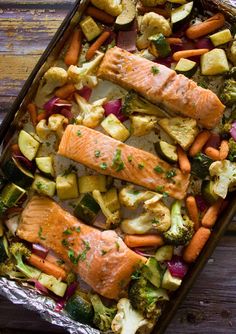 salmon and vegetables in a baking pan on a wooden table