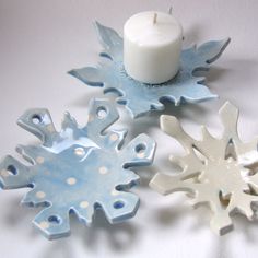 three snowflakes are sitting next to a candle