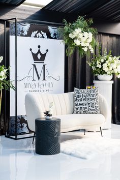 a white couch sitting on top of a white floor next to two vases filled with flowers