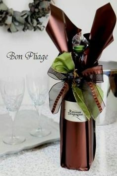 a wine bottle wrapped in brown paper and tied with a green ribbon, sitting on a counter