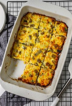 a casserole dish on a cooling rack with utensils next to it