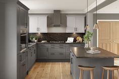 a large kitchen with wooden floors and gray cabinets