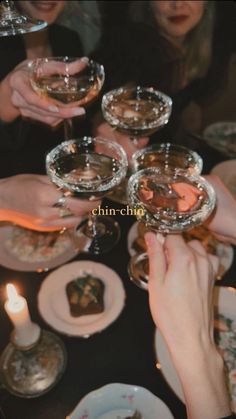 several people are toasting with wine glasses at a table full of food and candles