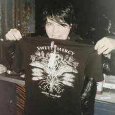 a woman holding up a black shirt with the words sweet mercy on it