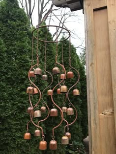 a wind chime hanging from the side of a wooden structure next to a tree