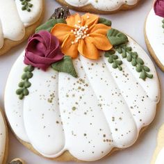 decorated cookies with white frosting and flowers on them are arranged in the shape of pumpkins