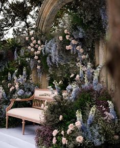 a bench sitting in the middle of a garden filled with lots of flowers and greenery