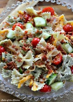 pasta salad with tomatoes, cucumbers, and other toppings in a glass bowl