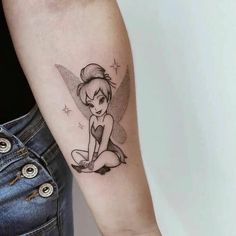 a woman's arm with a small tattoo of a tinkerbell on it