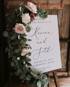 a wedding sign with flowers and greenery is displayed on an easel in front of a wooden wall