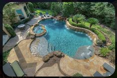 an aerial view of a swimming pool surrounded by trees and shrubs, with lounge chairs around it