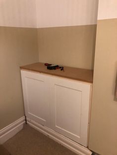 there is a small white cabinet in the corner of this room, with tools on it