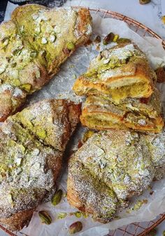 several pastries sitting on top of a plate covered in powdered sugar and pistachio