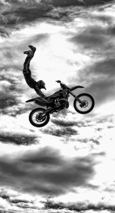 a man flying through the air on top of a dirt bike in front of a cloudy sky