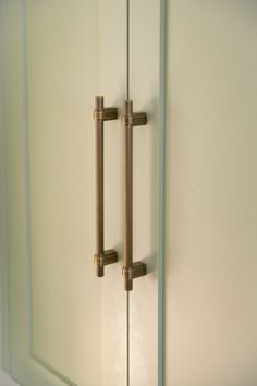 two handles on the front of a white cabinet