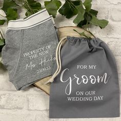 two personalized gray and white wedding gifts in drawstring bags, one for the new groom