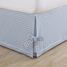 a blue and white checkered bed skirt with a bow at the end on a wooden floor