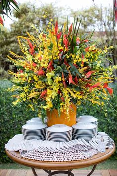 a table topped with plates and vases filled with flowers on top of a wooden table