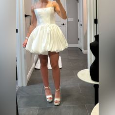 a woman in a short white dress taking a selfie