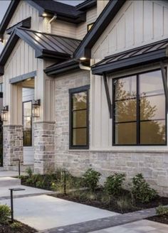 an exterior view of a home with stone and brick sidings, windows, and landscaping