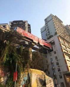 a red train traveling over a bridge in the middle of a city with tall buildings