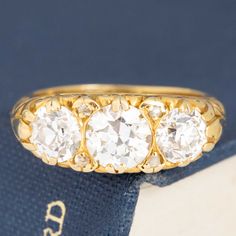 Beautifully crafted Victorian revival ring with truly gorgeous scroll details along the gallery and shank. Set with 3 perfectly matched OECs, which psrakle beautifully in this rich yellow gold setting. Low set and so elegant on the finger! 18kt Yellow Gold Size 5.75 & Resizable Diamonds are estimated to be I/J colors & VS-SI clarities. GIA Standards Please see qualitative report for more information. Classic Gold Three-stone Rings, Luxury Gold Three-stone Ring, Luxury Gold Three Stone Ring, Gold Three Stone Diamond Ring With Round Band, Luxury Gold Three Stone Diamond Ring, Heirloom Yellow Gold Three Stone Ring, Victorian Three Stone Round Cut Ring, Victorian Three-stone Round Cut Ring, Victorian Gold Three Stone Ring