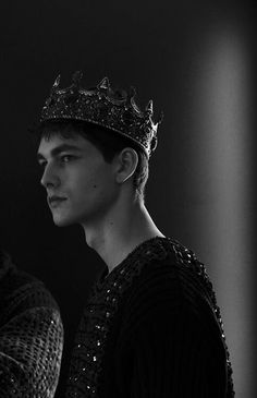 a man wearing a crown standing in front of a black background