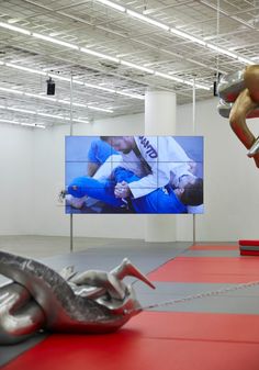 an indoor gym area with equipment on the floor and a large screen in the background