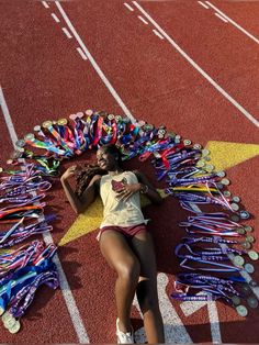 a woman laying on the side of a running track surrounded by ribbons and medals,