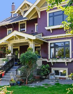 a purple house with lots of windows and flowers in the front yard on a sunny day