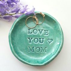 a green plate with two wedding rings on it and the words love you mom written in cursive font