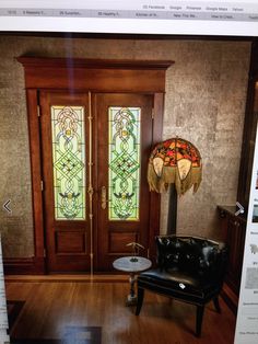 a chair and lamp in front of a wooden door with stained glass panels on it