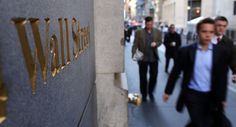 two men walking down the sidewalk in front of a wall with gold lettering on it