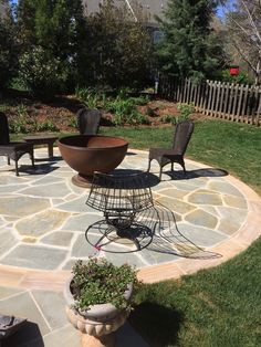 a stone patio with chairs and table in the middle