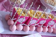 there are many pink and white treats on the table with candy sticks in them,