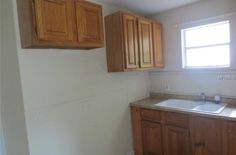 an empty kitchen with wooden cabinets and white walls