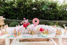 a table topped with lots of pink and gold decorations on top of a white table