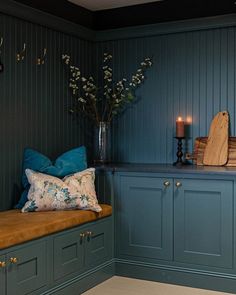 a kitchen with blue painted cabinets and wooden counter tops, along with a bench that has pillows on it