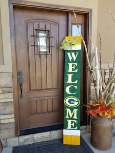 a welcome sign next to a potted plant and wooden door with the word welcome on it