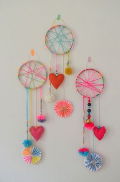 a group of colorful wind chimes hanging from the side of a wall next to a white wall