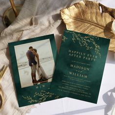 two wedding cards on top of a table next to a gold plate and a golden leaf