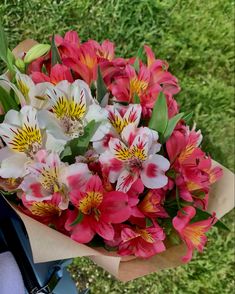 a bouquet of pink and white flowers sitting on top of a grass covered field