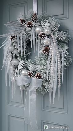 a christmas wreath hanging on the front door with pine cones and silver baubies